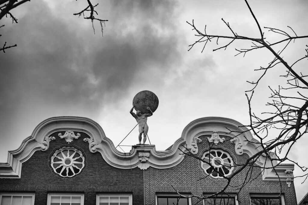 Zwart-wit foto van het Atlas standbeeld op een historische gevel in Utrecht