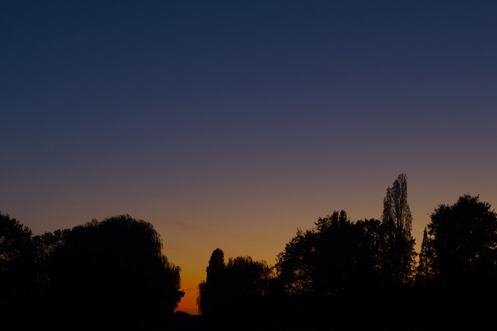 Blauwe avondlucht met oranje gloed boven Heythuysen